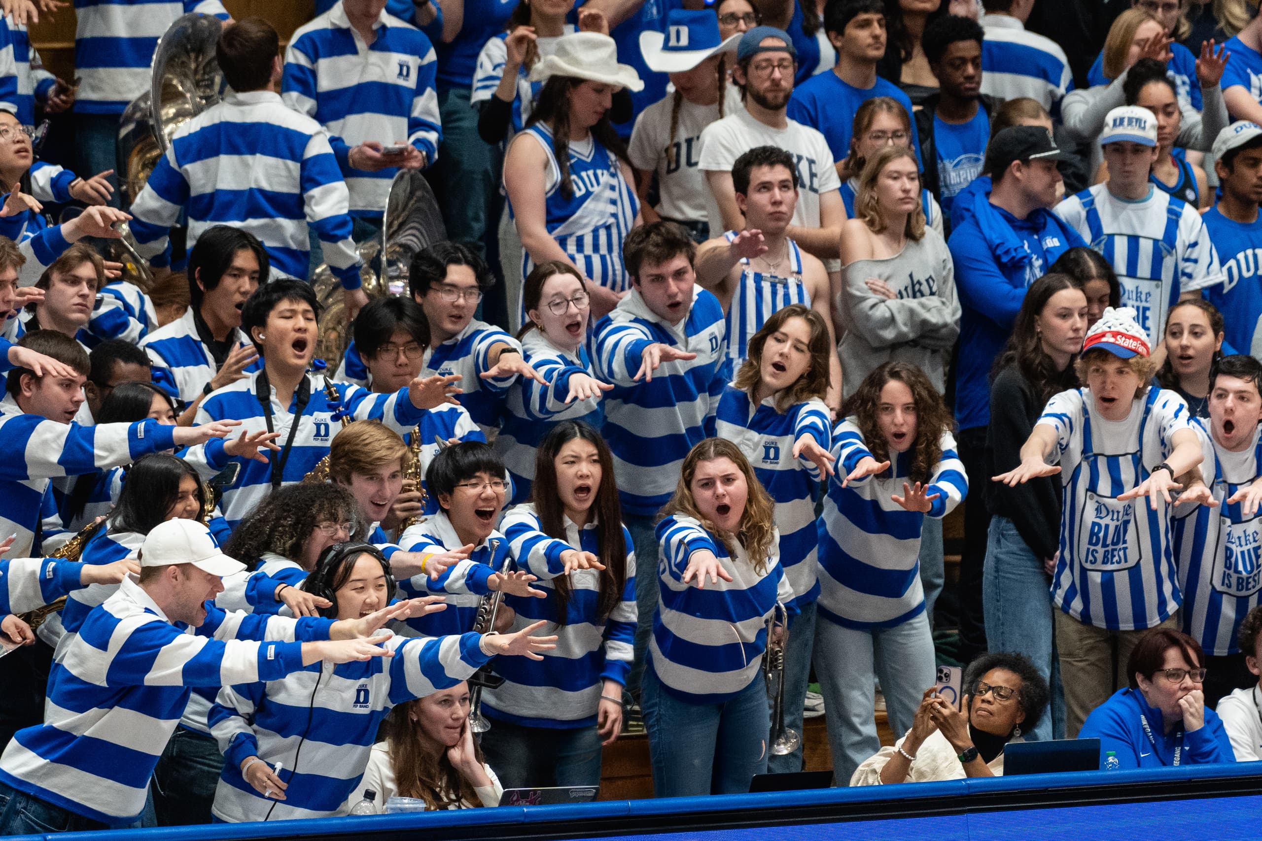The Duke student section on their feet with arms outstretched toward the court